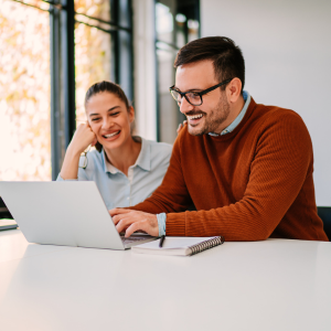 Man and Woman smiling at laptops