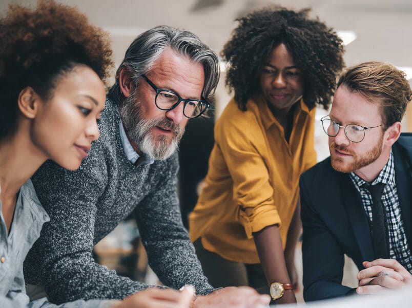 A group of IT professionals individuals intently reviewing a tablet together, fostering teamwork and innovation through technology.