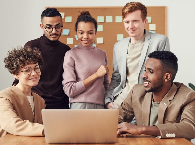 A team of IT professionals individuals intently looking at a laptop, sharing thoughts and strategies in a collaborative environment.