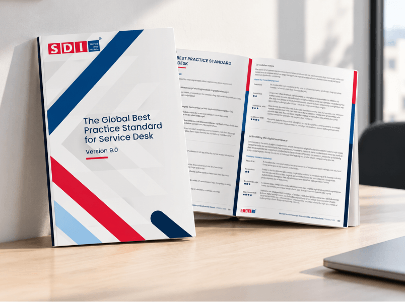 An open book titled The Global Best Practice Standard for Service Desk Version 9.0 resting on a wooden desk.
